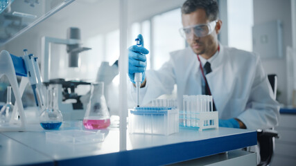 Medical Development Laboratory: Male Scientist Uses Micro Pipette for Filling Test Tubes with...