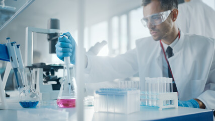 Fototapeta premium Medical Development Laboratory: Male Scientist Uses Micro Pipette for Filling Test Tubes with Liquid, Conducting Experiment. Big Pharmaceutical Lab with Specialists Research Medicine, Biotechnology