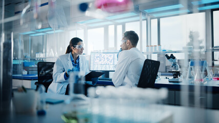 Modern Medical Research Laboratory: Portrait of Two Scientists Working, Using Digital Tablet, Analyzing Samples, Talking. Advanced Scientific Pharmaceutical Lab for Medicine, Biotechnology Development