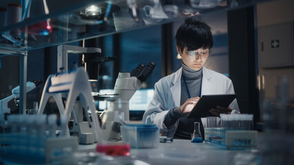 Medical Development Laboratory: East Asian Scientist Uses Digital Tablet Computer, Uses Microscope,...