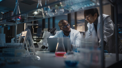 Modern Medical Research Laboratory: East Asian and Black Scientists Work on Laptop, Do Data...