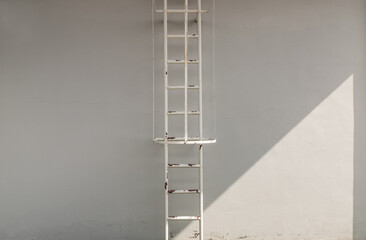 White metal fire escape attached to a wall and leading to the roof of a building. Copy space, No...