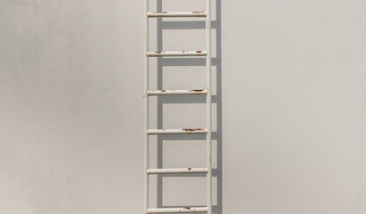White metal fire escape attached to a wall and leading to the roof of a building. Copy space, No...