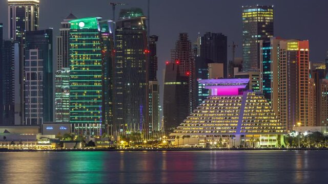 Doha downtown skyline day to night transition timelapse, Qatar, Middle East. Illuminated skyscrapers on a West Bay reflected in a water of Gulf. View from MIA park