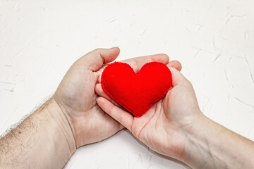 Male and female hand are holding a homemade felt heart