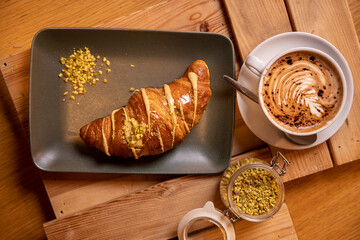 breakfast with creamy croissant, pistachio nuts and cappuccino