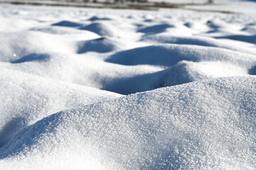 Close-up of a snow covered field. The snow looks like white sand dunes.