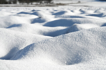 Obraz premium Close-up of a snow covered field. The snow looks like white sand dunes.