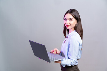 Young business woman stands with laptop in her hands.