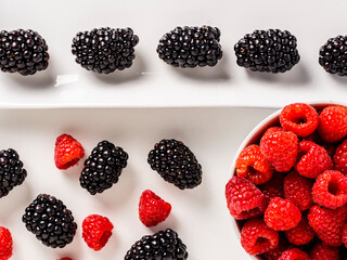 Overhead shot of raspberries and blackberries on white background.