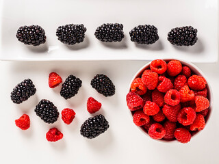 Overhead shot of raspberries and blackberries on white background.