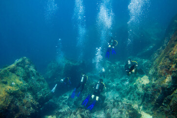 Group of divers over the ocean floor reef boulders