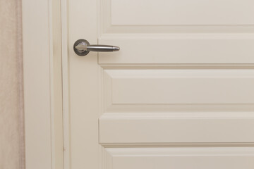 Classic white wooden milled door with chrome handle. White Scandinavian interior