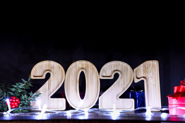 Happy New Year Wooden Number 2021 as text with flowers and Giftbox on black background, selective...