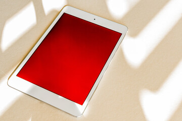 Tablet with red screen on a desk. Copy space. Technology concept.