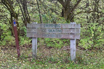 The old wooden warning sign in the park on the trail.