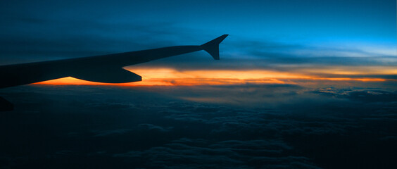 Sun creeping in the horizon, view from airplane above the clouds.