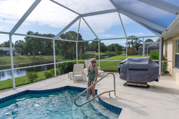Retired Woman wading into pool in Florida