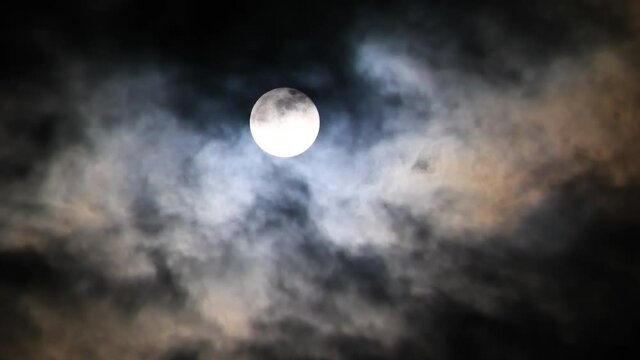 The full moon rising among clouds
