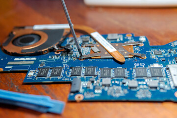 Repairing a laptop motherboard on a wooden desk