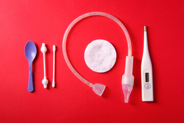 Children's nasal aspirator, cotton swabs, thermometer, on a red background