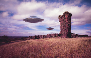 Two UFOs flying over ancient rocks. Unidentified flying objects flying over the sky. 3D illustration with clipping mask included. © ktsdesign
