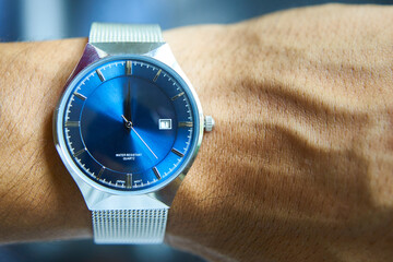 Reloj pulsera metálico azul con fecha en muñeca de hombre. Primer día del año y del mes