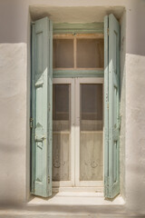 Green opened window shutters before glass windows with white curtains in the town of Kapsali on Kythira Greece