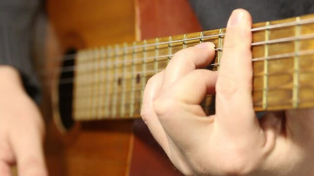 A man plays a six-string acoustic guitar. Plays several chords.
