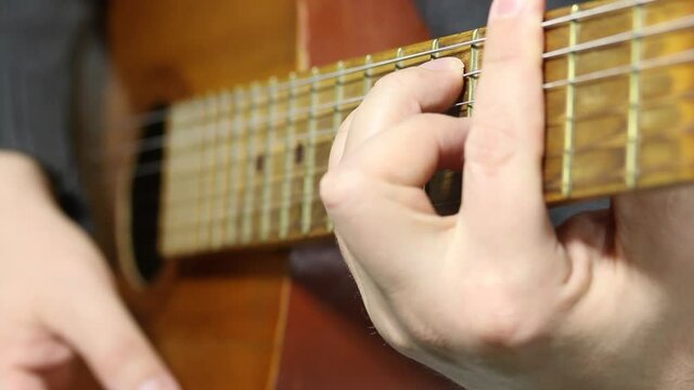 A man plays a six-string acoustic guitar. Plays in combat. Plays several chords.