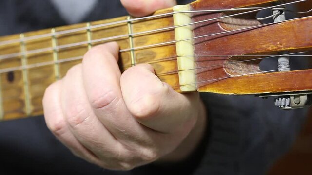 A man plays a six-string acoustic guitar. Takes chords. Close-up shot of the guitar fretboard and chords being played