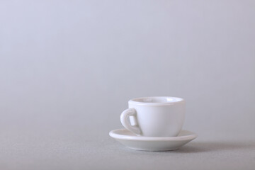 white cup on a saucer isolated on gray background