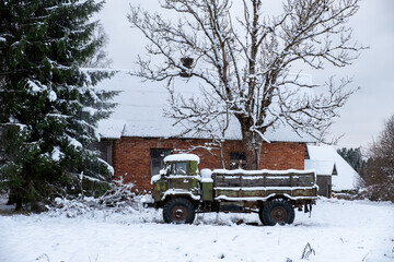 An old Soviet-era truck is parked outside a country house in the winter