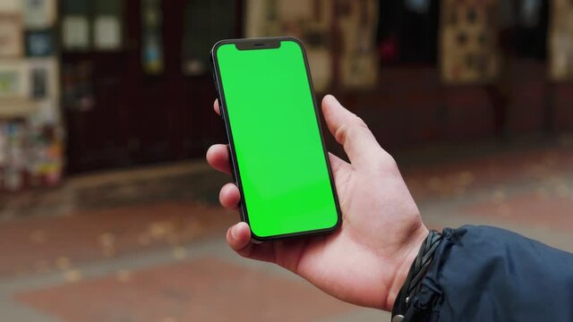 Hands man using phone with vertical green screen background on street terace city blurred internet chrome outdoor. Cellphone media device. Slow motion
