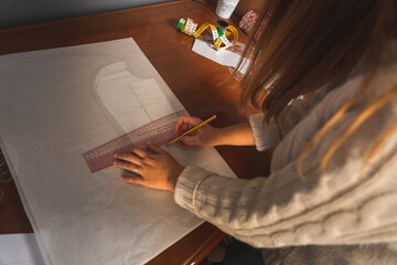 Young dressmaker working on clothes patterns