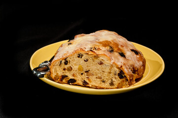 top, front view, medium, close distance of a Christmas stollen loaf, handle of a knife, on a round gold plate with black background