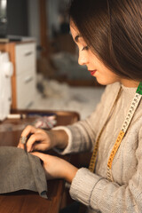 Fototapeta premium Young dressmaker working on the studio with textiles
