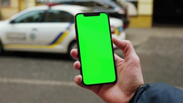 Young Hands Man Using Phone With Vertical Green Screen Background Police Car On City Blurred Internet Chrome Outdoor. Cellphone Media Device. Slow Motion