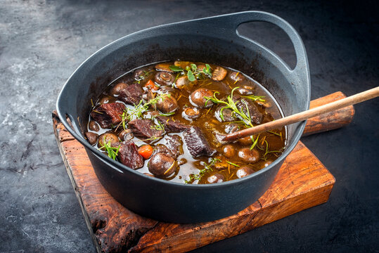 Modern style traditional French boeuf bourguignon with mushrooms and carrots in red wine sauce served as close-up in a Design casserole