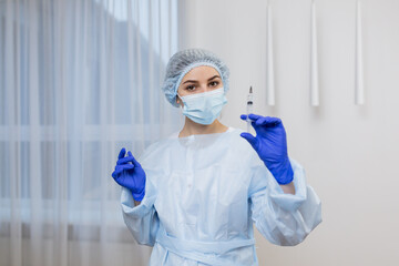 Young woman-doctor in medical uniform and gloves holds an injection in her hands. healthcare and medical concept - close up photo