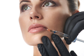 Young beautiful woman receiving injection of filler in lips. Injection cosmetology. Closeup on...