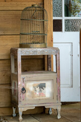 A vintage birdcage sitting on an antique cabinet