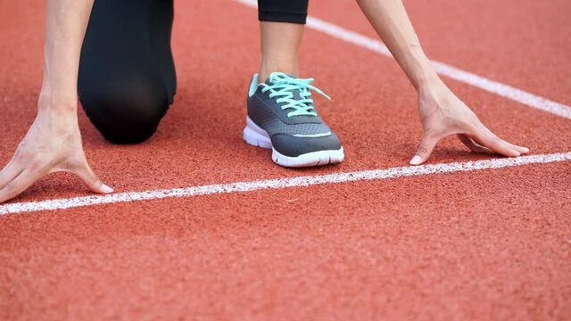 Close up young  female athlete is launching off the start line in a race in athletics stadium