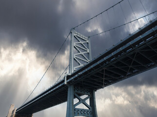 View of the historic Benjamin Franklin Bridge with storm sky in Philadelphia Pennsylvania.