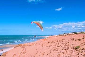 Kiteboarding or kitesurfing in Canoa Quebrada beach. It is an extreme sport where the kiteboarder harnesses the power of the wind with a large controllable power kite to be propelled across the water.