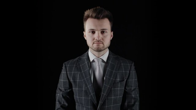 Handsome confident businessman wearing suit isolated on black background. Half-length portrait of young caucasian man with beard wear plaid blazer business suit looking at camera, serious look