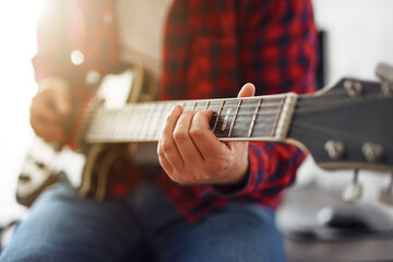 Stylish guy learning to play the guitar at home. Video communication training. Distance learning....