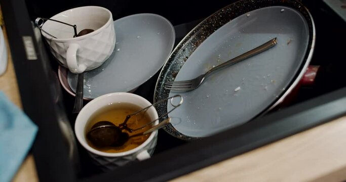Lots of unwashed and dirty dishes in the kitchen sink. Slow motion.