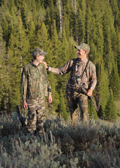 father and son bow hunting and interracting in woods full-length
