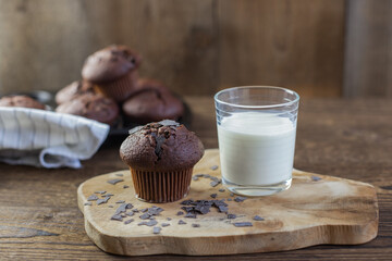 Homemade freshly baked muffins next to a glass of milk on a rustic wooden background. Breakfast. Fresh bakery